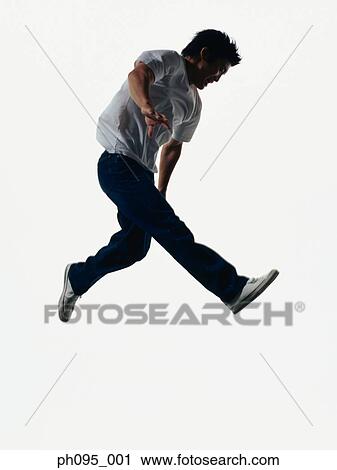 Stock Image - Young Asian man in jeans & t-shirt, jumping in mid-air. Fotosearch