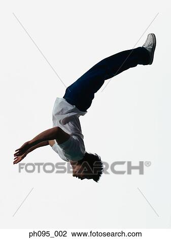 Stock Image - Young Asian man in jeans & t-shirt, jumping in mid-air. Fotosearch