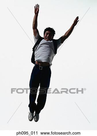 Young Asian man in jeans & t-shirt, carrying haversack, jumping in mid-air View Large Photo Image Stock Image - Young Asian man in jeans & t-shirt, carrying haversack, jumping in mid-air. Fotosearch