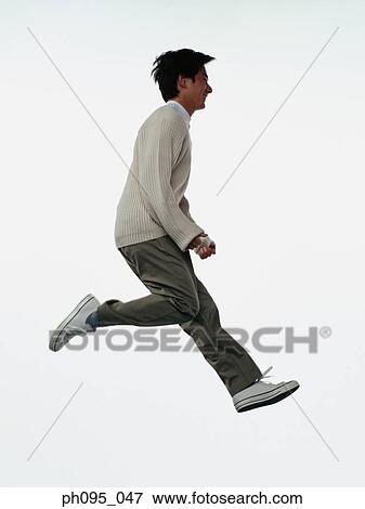 Stock Photo - Young Asian man in pants & sweat-shirt, jumping in mid-air. Fotosearch