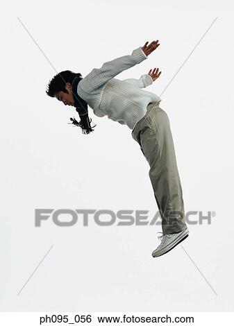 Stock Photograph - Young Asian man in pants & sweat-shirt and scarf, jumping in mid-air. Fotosearch