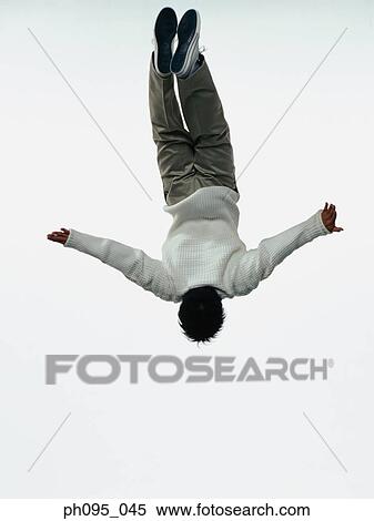 Stock Photography - Young Asian man in pants & sweat-shirt, jumping in mid-air. Fotosearch