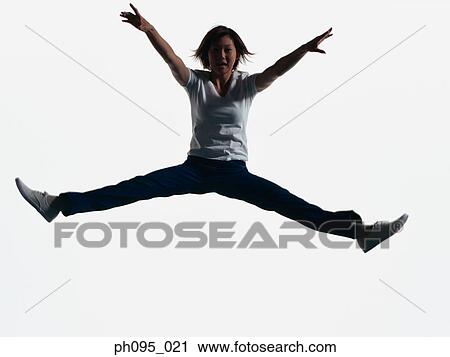 Stock Image - Young Asian woman in jeans & t-shirt, jumping in mid-air. Fotosearch