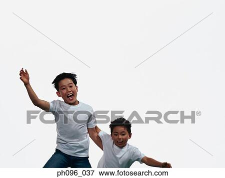 Two young Asian boys in jeans & t-shirt, jumping in mid-air View Large Photo Image Stock Photo - Two young Asian boys in jeans & t-shirt, jumping in mid-air. Fotosearch
