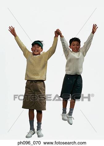 Stock Image - Two young Asian boys in shorts & sweat-shirts, jumping in mid-air. Fotosearch
