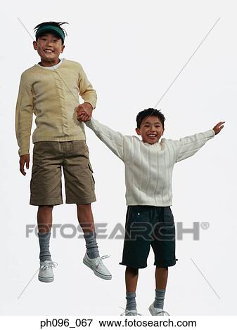 Two young Asian boys in shorts & sweat-shirts, jumping in mid-air View Large Photo Image Stock Photo - Two young Asian boys in shorts & sweat-shirts, jumping in mid-air. Fotosearch