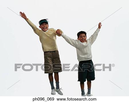 Stock Photo - Two young Asian boys in shorts & sweat-shirts, jumping in mid-air. Fotosearch