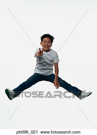 Stock Image - Young Asian boy in jeans & t-shirt, jumping in mid-air. Fotosearch