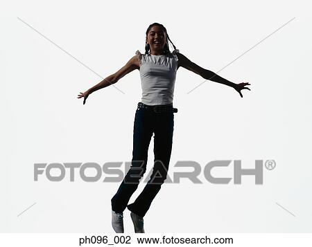 Stock Image - Young Asian girl in jeans & t-shirt, jumping in mid-air. Fotosearch