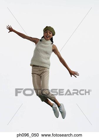 Stock Image - Young Asian girl in shorts & cardigan, jumping in mid-air. Fotosearch