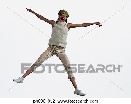 Stock Image - Young Asian girl in shorts & cardigan, jumping in mid-air. Fotosearch