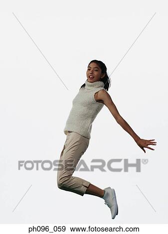 Stock Photo - Young Asian girl in shorts & cardigan, jumping in mid-air. Fotosearch