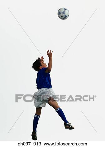 Stock Image - Young Asian boy jumping to head soccer ball in mid-air. Fotosearch