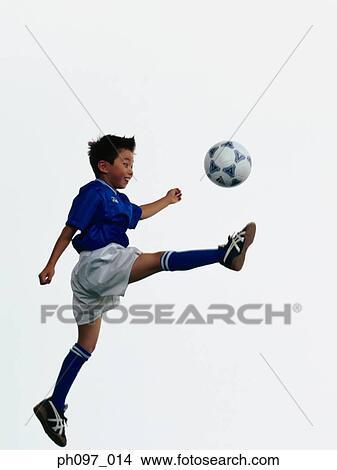 Young Asian boy kicking football in mid air View Large Photo Image Picture - Young Asian boy kicking football in mid air. Fotosearch