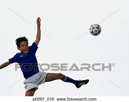 Young Asian boy kicking football in mid air View Large Photo Image Stock Photograph - Young Asian boy kicking football in mid air. Fotosearch