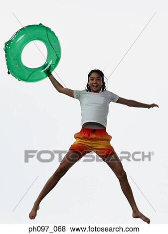 Stock Photo - Young Asian girl holding inflated ring, jumping in mid-air. Fotosearch