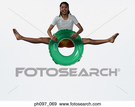 Stock Photo - Young Asian girl holding inflated ring, jumping in mid-air. Fotosearch