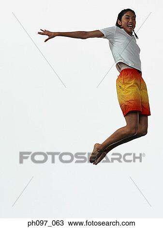 Stock Image - Young Asian girl in shorts & t-shirt, jumping in mid-air. Fotosearch