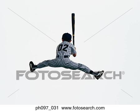 Stock Image - Young Baseball player holding bat in mid-air, rear view. Fotosearch