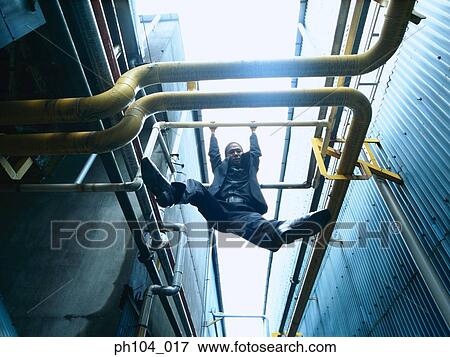 Man hanging on pipes, low angle view View Large Photo Image Stock Photo - Man hanging on pipes, low angle view. Fotosearch
