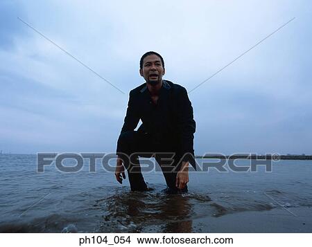 Man kneeling at the beach in pain View Large Photo Image Picture - Man kneeling at the beach in pain. Fotosearch