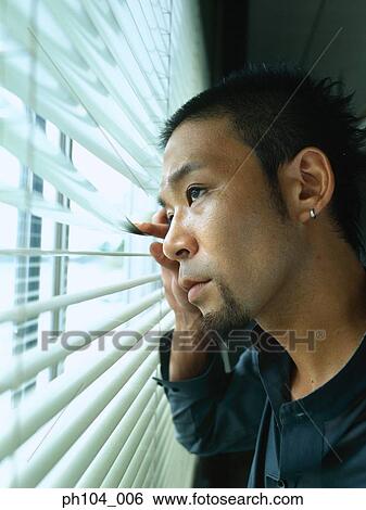 Stock Photograph - Man looking out window blinds. Fotosearch