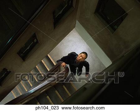 Man looking up at railings of stairwell View Large Photo Image Stock Image - Man looking up at railings of stairwell. Fotosearch