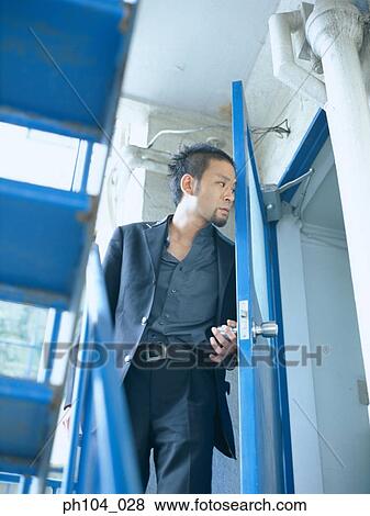 Man opens door discreetly, peeking inside View Large Photo Image Stock Photo - Man opens door discreetly, peeking inside. Fotosearch