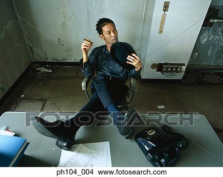 Man resting feet on table, smoking View Large Photo Image Picture - Man resting feet on table, smoking. Fotosearch