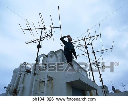 Man standing at roof top, looking for something View Large Photo Image Stock Photograph - Man standing at roof top, looking for something. Fotosearch