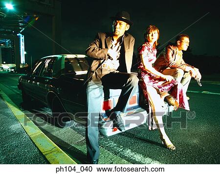 Two men and a woman sitting on car View Large Photo Image Stock Image - Two men and a woman sitting on car. Fotosearch