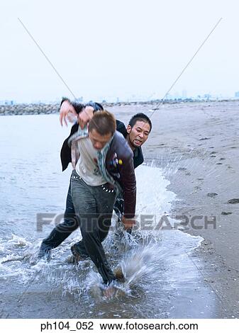 Stock Image - Two men struggling at the beach. Fotosearch