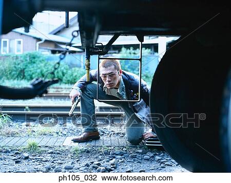 man hiding under a train, holding a pistol View Large Photo Image Stock Image - man hiding under a train, holding a pistol. Fotosearch