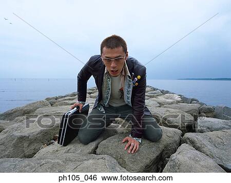 Man kneeling, one hand holding a briefcase View Large Photo Image Stock Photograph - Man kneeling, one hand holding a briefcase. Fotosearch