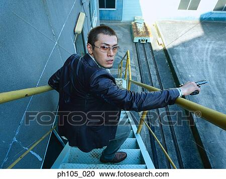 Stock Image - Man looking over his shoulder on a flight of staircase. Fotosearch
