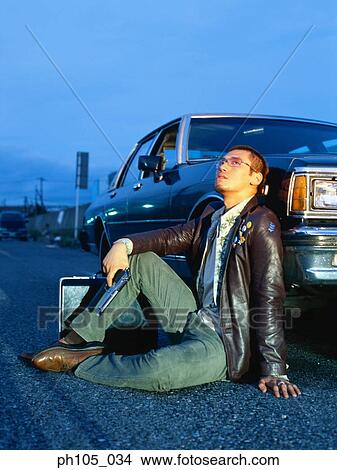 Man sitting against a car View Large Photo Image Picture - Man sitting against a car. Fotosearch