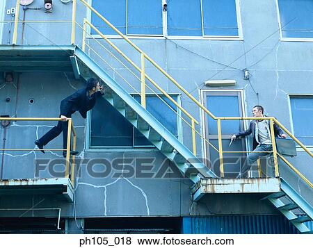 Stock Photo - Two men in different flights of stairs. Fotosearch