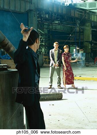 Stock Photograph - Two men with guns and a lady in Chinese costume. Fotosearch