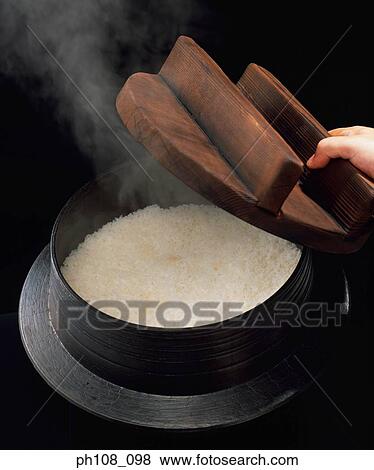 Stock Photo - Removing the wood cover from rice cooker. Fotosearch