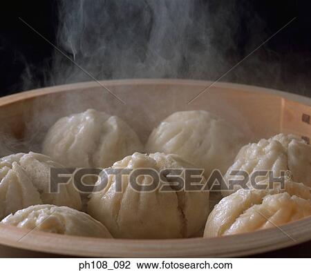 Stock Image - Steam buns in bamboo basket, close-up. Fotosearch