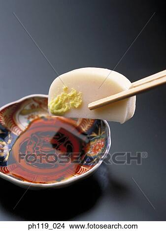 Picture - Dipping a slice of fishcake in soya sauce. Fotosearch
