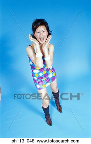 Stock Photo - Portrait of a woman holding her hands to her cheeks with an expression of pleasant surprise. . Fotosearch
