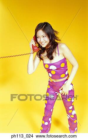 Picture - Woman in polka dot suit, on the phone, smiling. Fotosearch
