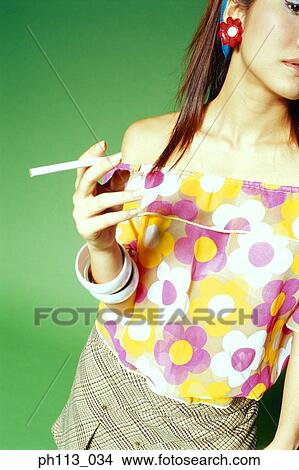 Picture - Young woman in floral blouse, holding a cigarette. Fotosearch