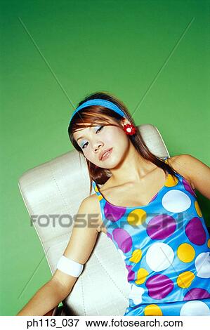 Stock Photo - Young woman in polka dot blouse, resting on couch. Fotosearch