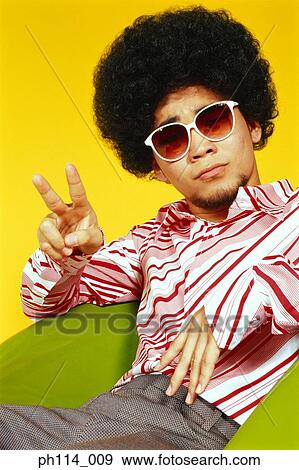 Stock Photo - Young Asian male with afro hair in sitting with victory pose. Fotosearch