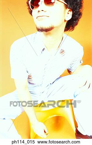 Stock Photography - Young Asian male with afro hair in sitting on ball chair. Fotosearch