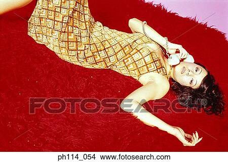 Picture - Young sexy woman on the phone, lying on carpeted floor. Fotosearch