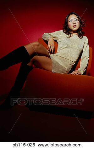 Stock Photography - Portrait of a young woman sitting on red couch. Fotosearch