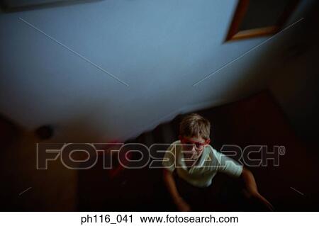 Stock Image - Young boy walking down stairs, looking up. Fotosearch